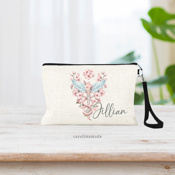 Floral caduceus medical symbol personalized with name in the corner on a linen wristlet with black strap.