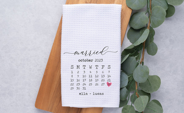 White Waffle Weave Tea Towel personalized with month of wedding date. Day is marked with a heart on it. Personalized with names at the bottom.