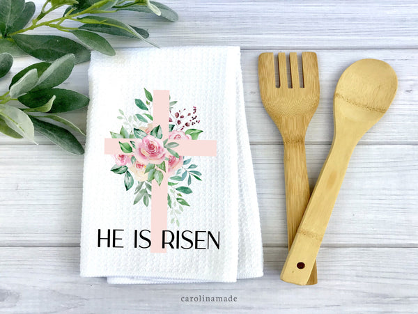 Easter Kitchen Tea Towel with large pink cross with flowers and greenery. Bottom says HE IS RISEN