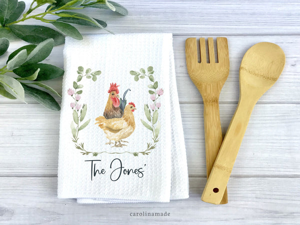 Farmhouse watercolor rooster and Hen design with greenery and flowers around it. Personalized with Family name at the bottom of the white waffle weave towel.