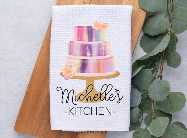 White Waffle Weave Towel with 3 tier colorful cake and flowers. Personalized with name at the bottom. Example says Michelle's Kitchen