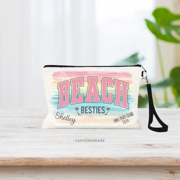This linen wristlet bag features a colorful background that has strokes of colors for sand, water, sunset. In large letters says BEACH BESTIES. And the corners are personalized with name, location and date.