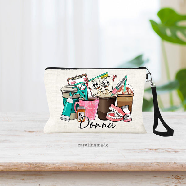 Linen wristlet makeup bag with dental items centered on the bag. Floss, Teeth, Tooth Brush, Tooth Paste, and of course Coffee! Personalized with name at the bottom.
