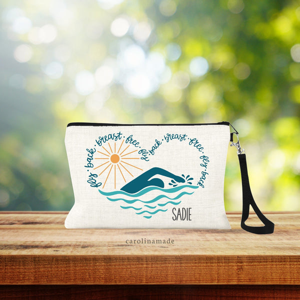 Personalized swimmer makeup bag that has a large heart with waves, swimmer, sun, and the text: fly, back, breast, free around it. Perfect gift idea for swim team!