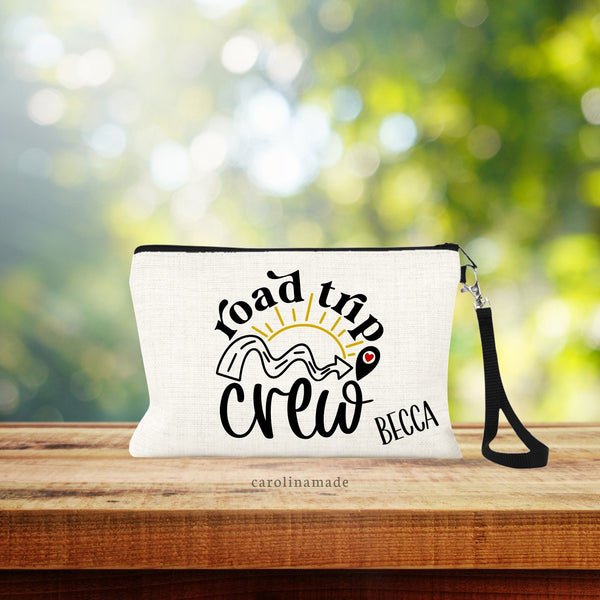Personalized Road trip zippered pouch features sun, road with an arrow to a heart. Text says road trip crew and is personalize in the bottom right corner with a name.
