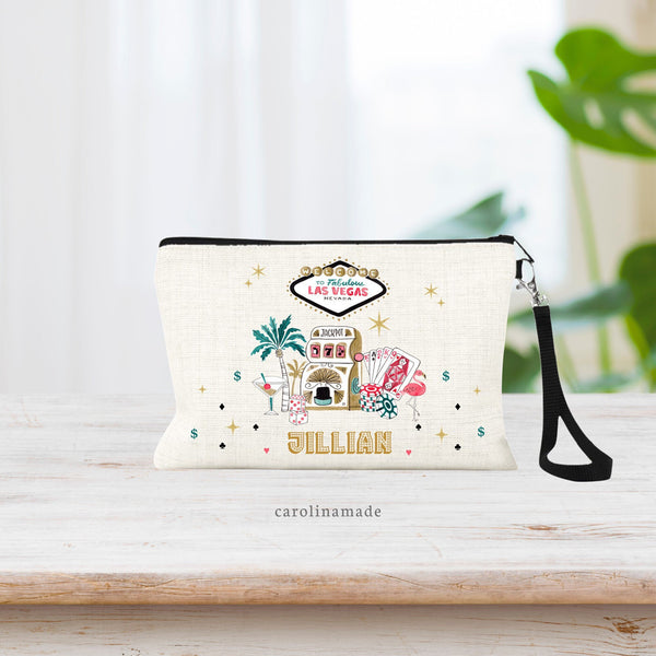 Vegas Party Favor zippered pouch features the vegas sign at the top and different casino clip art in the center. Slot machine, cards, chips, martini, dice, flamingo. Name is personalized at the bottom in a casino style font.