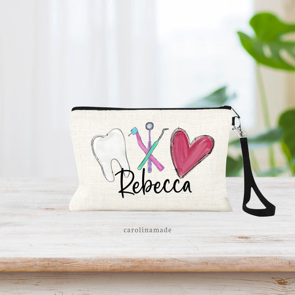 This zippered pouch shows a tooth, dental tools and a heart large centered on the bag with a personalized name underneath.