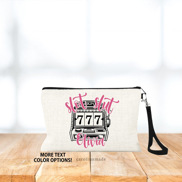 This linen wristlet features a slot machine in the center of the bag with the text slot slut at the top and name personalized at the bottom