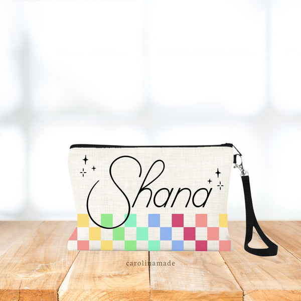 This zippered pouch features multi color checkered pattern on the bottom portion of the bag with a name personalized large at the top.