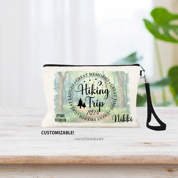 This linen zipper pouch features a circle that says: Hiking Trip, with stars, moon, trees. The year is noted at the bottom. Personalize with your name and destination. Background shows woods, trees, and trail for beautiful hiking scene.