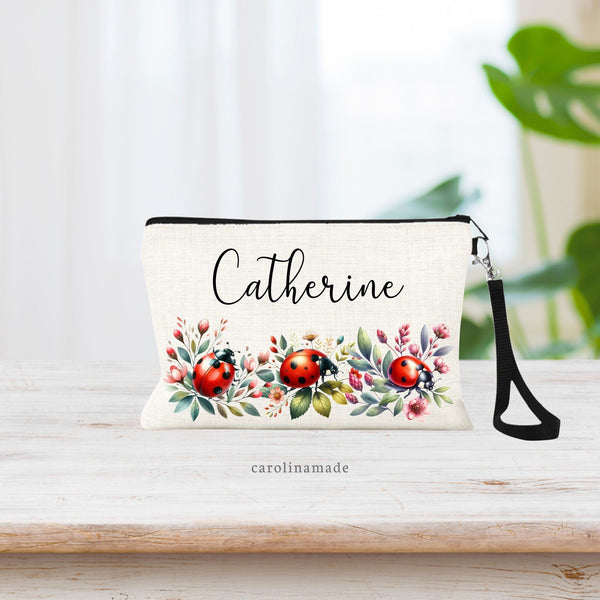 This beautiful natural linen wristlet features a personalized name at the top. Along the bottom of the bag is greenery, spring flowers and 3 red ladybugs.