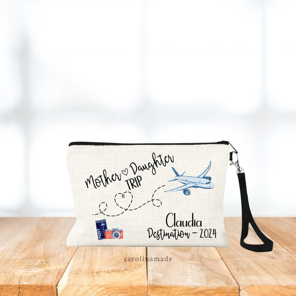 Headed on a getaway as Mother Daughter?! This bag is for you! Text says: Mother Daughter trip at the top with ticket, camera & airplane design. The bottom corner is personalized with your name, destination, and date.