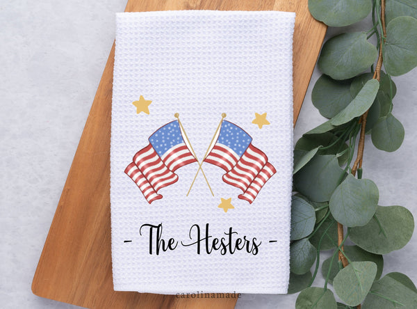 This white waffle weave towel features a watercolor Red white & blue double United States Flag design. The bottom is personalized with your family name. And Gold stars surround the design
