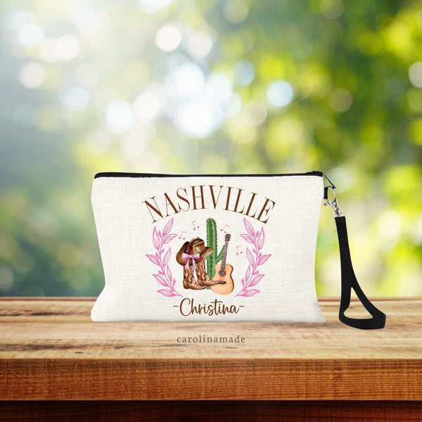 This personalized linen zipper pouch has your name at the bottom with Nashville at the top, pink wreaths on the side with guitar, cowgirls boots, hat and cactus in the center.