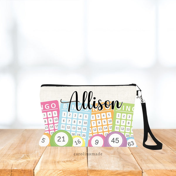 This linen wristlet bingo zipper pouch features 4 bright color bingo cards with colorful bingo balls at the bottom. It is personalized with your name at the top.