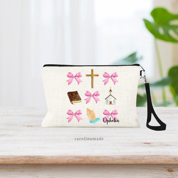 This linen wristlet features pink watercolor coquette bows in a pattern with church items. The Cross, Bible, Praying Hands & Church. The perfect gift for baptism, First communion, Confirmation. Personalize this pouch with a name at the bottom.