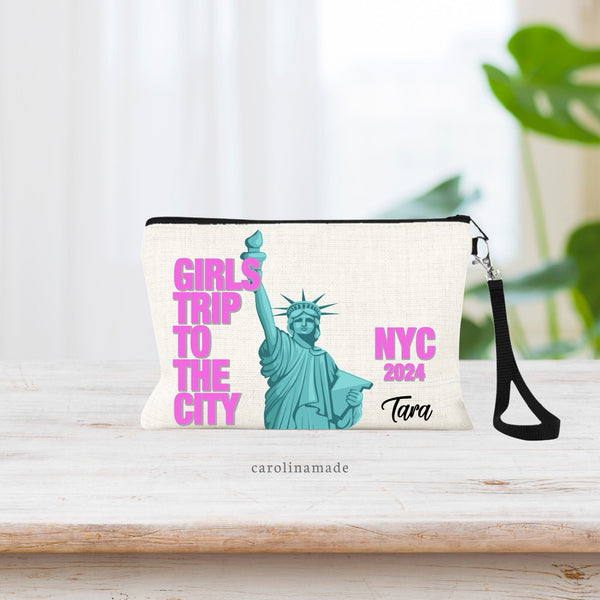 This linen wristlet features the Statue Of Liberty large in the center of the bag with the text: Girls Trip to the City in a bright pink to the left. And NYC 2024 to the right. Your name is personalized on the bottom right corner. Must have for NYC!