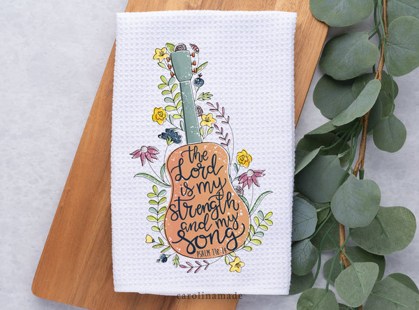 This white waffle weave towel features a beautiful floral guitar design that says in black script The Lord is my strength and my song. Psalm 118 14.