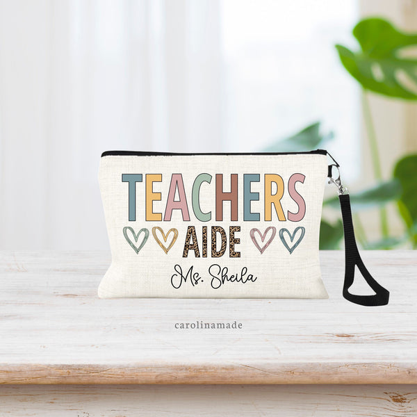 Colorful Teacher's Aide zipper pouch with TEACHER is large letters and AIDE in leopard print. Surrounded by hearts. And personalized at the bottom with your favorite Teachers aides name.