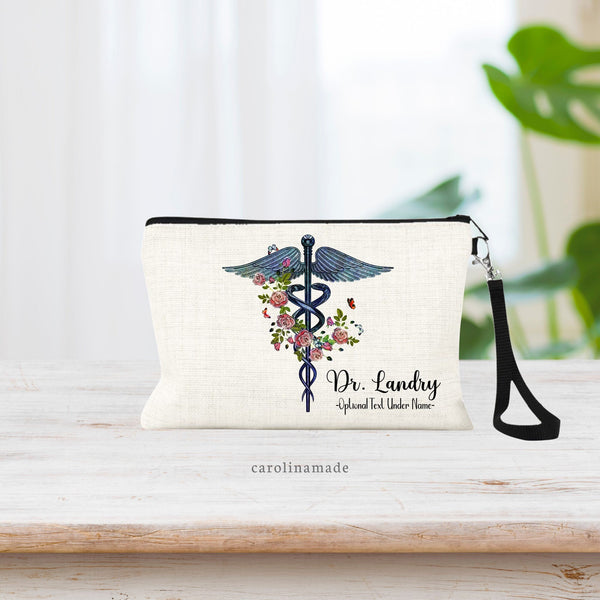 This linen zipper pouch is perfect for doctors, nurses, medical professionals & more! The blue Floral caduceus medical symbol is in the center with greenery and pink flowers around it. Personalize the corner with a name and optional text.