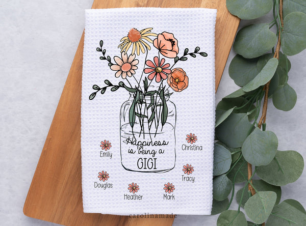 This white waffle weave towel features a beautiful flower bouquet in a mason jar that says Happiness is being a where you personalize the last word. Mom, Grandma, Gigi, Nana, Mimi, whatever you want! Around the jar has flowers with grandkids names.