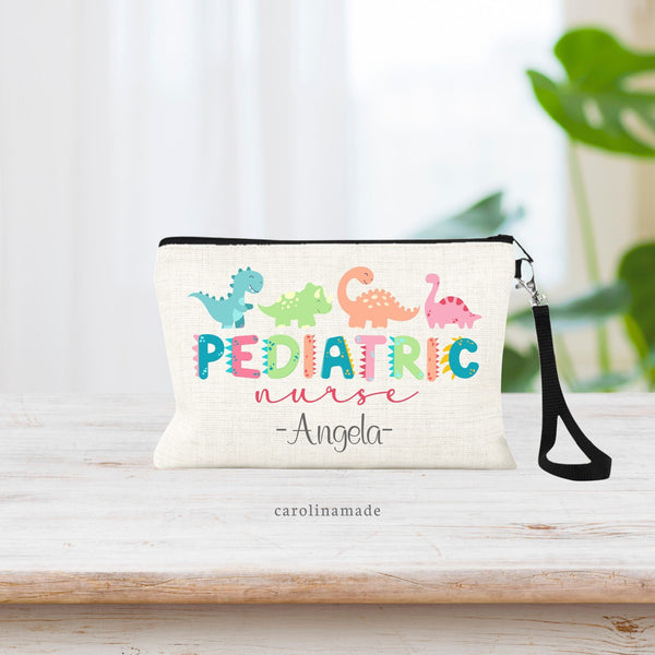 This linen zipper pouch features the text PEDIATRIC on a fun colorful dinosaur font with spikes on the letters. Nurse is under it. There are 4 dinos at the top. And the bottom of the bag is personalized with your name.