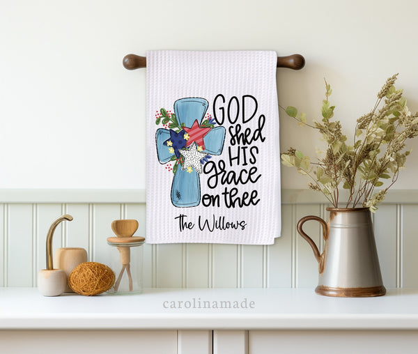This white waffle weave towel has a blue cross with patriotic red white and blue stars on it with the quote God shed His grace on thee. The towel is personalized at the bottom with your family name.