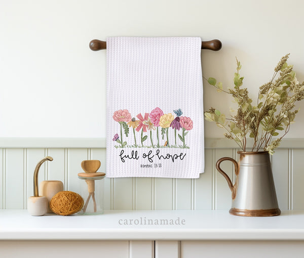 This white waffle weave towel features the design that says full of hope romans 15 13 and has beautiful hand drawn wildflowers.