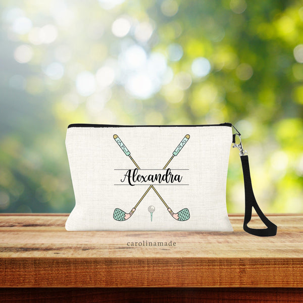 This linen zipper pouch features two golf clubs crossed each other with a name personalized in the center. Golf clubs are in a fun whimsical print. With golf ball and tee at the bottom.