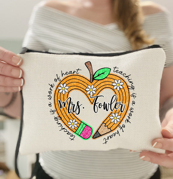 Linen zipper pouch with black lining inside features a yellow pencil in the shape of a heart with your personalized teachers name over top of it. Outside the heart it says Teaching is a work of heart