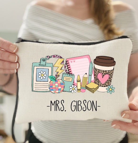 This linen wristlet shows teacher icons -notebook, badge, apple, pencil, crayon, pen, sticky notes, coffee and flowers. There is a name personalized at the bottom.