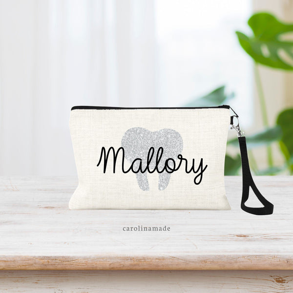 This zippered pouch shows a large tooth in the background in your choice of printed gold, rose gold or silver. Your name is personalized over top of tooth.