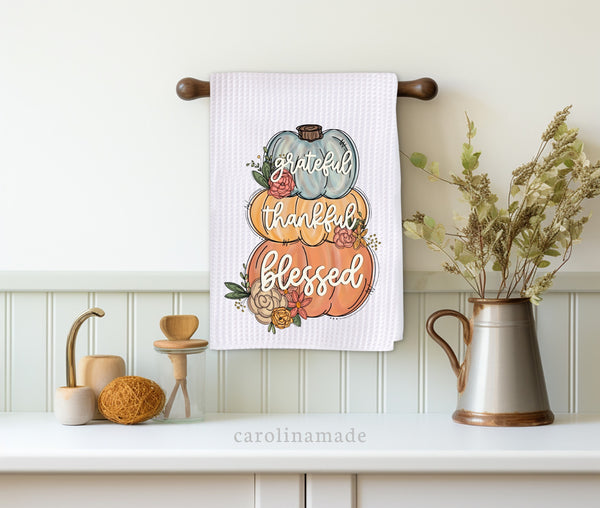 This white waffle weave towel features three fall stacked pumpkins that say grateful thankful blessed