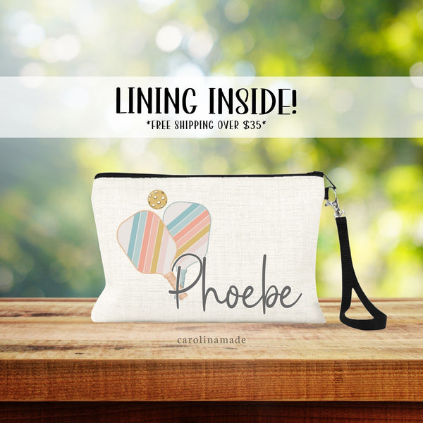 Linen wristlet with strap features pastel colored pickleball paddles and ball. Personalized with your name!