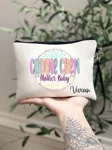 This linen bag lined with black lining features a colorful design on the outside that says Cuddle crew Mother Baby.  It is personalized in the bottom corner with your name.