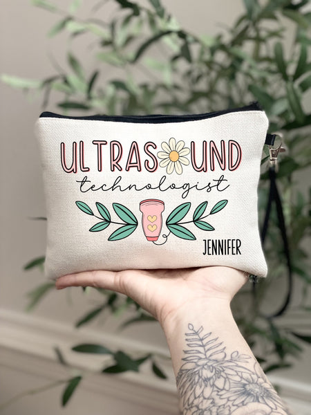 This linen zipper pouch features a fun trendy boho design in pink and green. It says ultrasound at the top with a daisy as the O. and technologist under it in script. A ultrasound wand is at the bottom with greenery & is personalized with your name.