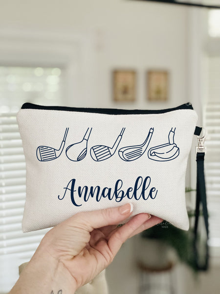 This linen zipper golf bag features a minimalist line art design with golf club heads. The pouch is personalized at the bottom with your name. Font and colors can be customized.