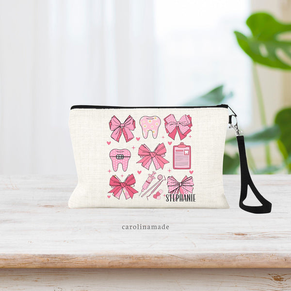 This beautiful linen wristlet pouch has a pink coquette bows and dentist items design featuring  pattern of bows, tooth, floss, dental tools, and clipboard. The bottom corner is personalized with your favorite dental employees name.