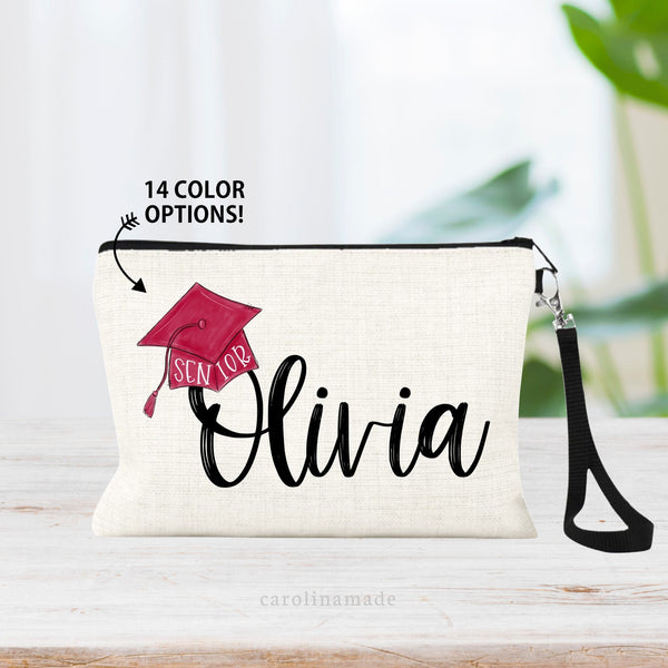 This linen wristlet features a minimalist design with a personalized name in the center and a graduation cap hanging off the first let. Customize the cap with 14 different school colors.