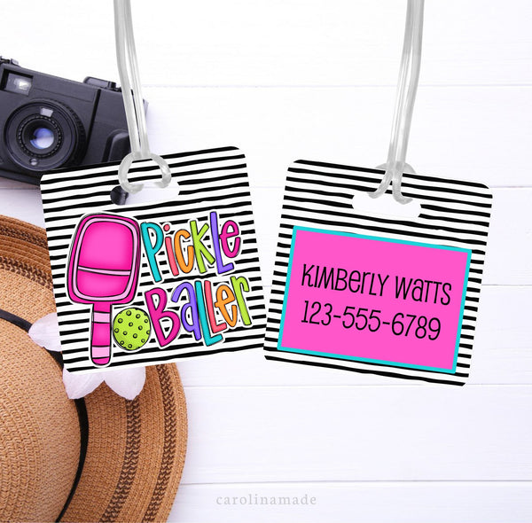 This aluminum tag shows black and white stripes on both sides. The front has a pink pickleball paddle and says Pickle Baller. The back is personalized with your contact info.