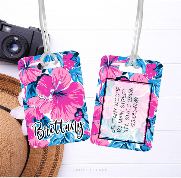 This aluminum luggage tag features a pink and blue preppy design with a large Hibiscus flower. The front has a name. And the back is personalized with contact info.