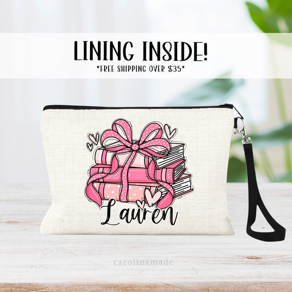 This linen zipper pouch is perfect for book lovers! It features a pink stack of books with bow and ribbon and hearts surrounding. personalize at the bottom with your name.