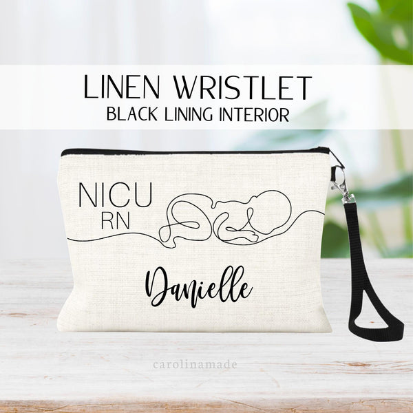This linen wristlet features a black zipper, black interior lining and a removable black strap. It shows a minimalist style line art of a baby on the front and says NICU RN on the top corner. It is personalized at the bottom with your name.
