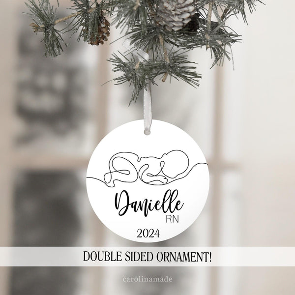 This white christmas ornament features a line art design with a baby in the center. It is personalized at the bottom with your name and nursing credentials. Perfect for labor and delivery, nicu, peds nurse and more!
