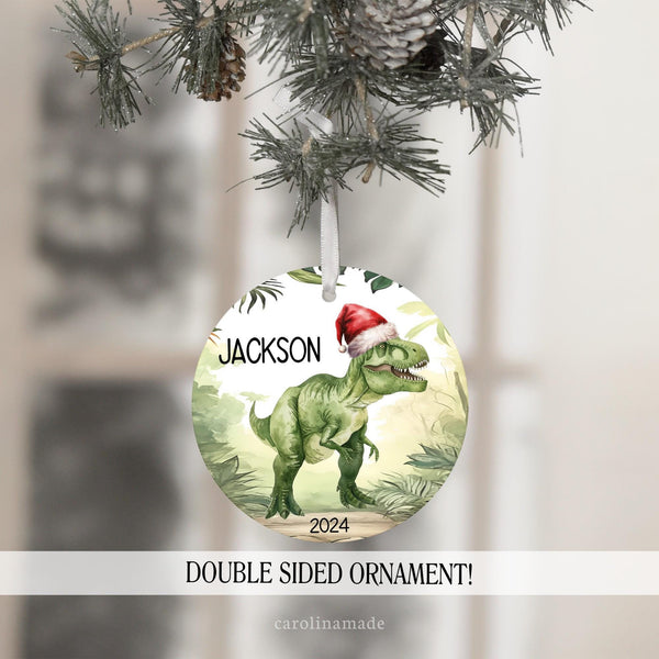 This fun Christmas ornament features a jungle theme background with a T Rex in the center wearing a Santa hat. It is personalized with the name and year. Perfect keepsake ornament for kids!