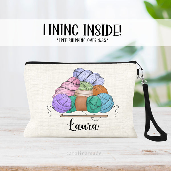 This linen zipper pouch features a stack of yarn in an assortment of colors. With a crotch hook under it. It is personalized at the bottom with your name.