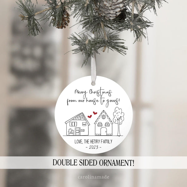 Minimalist line art christmas ornament that says merry christmas from our house to yours with two houses and two red hearts in between them. it is personalized at the bottom with your family name and the year.