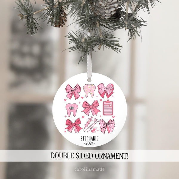 This preppy trendy design features pink bows in a pattern with dental items. - tooth, floss, clipboard, and dental tools. It is personalized at the bottom with a name and the current year.