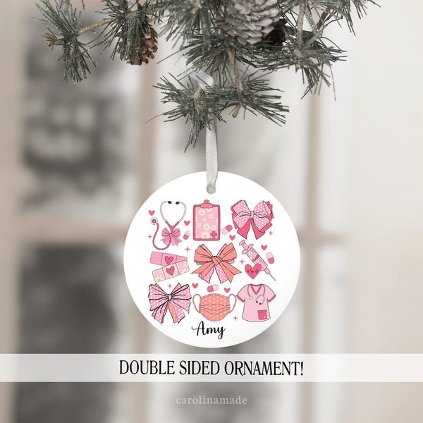 This ornament features pink bows and nursing elements - stethoscope, clipboard, need, bandage, mask. It is personalized at the bottom with a name.  Perfect ornament for medical workers!