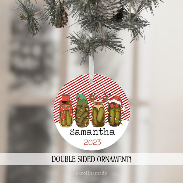 This christmas ornament features a red & white stripe background with 4 pickle jars that have different designs. Snowman Hat, Elf Hat, Reindeer, and a santa hat. It is personalized with name and year.